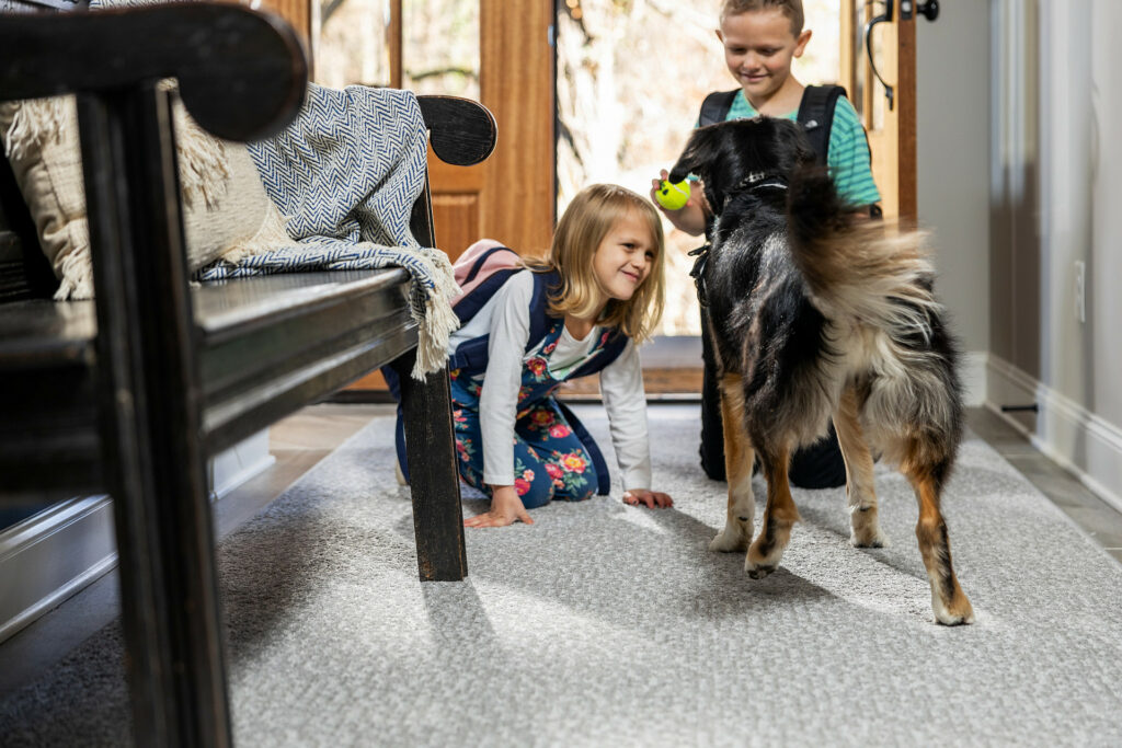 Kids plying with dog on carpet flooring | Puckett's Flooring